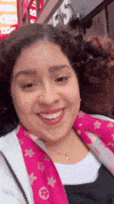 a woman wearing a pink louis vuitton scarf smiles