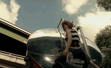 a woman is riding on the back of a silver truck with the letter a on the side