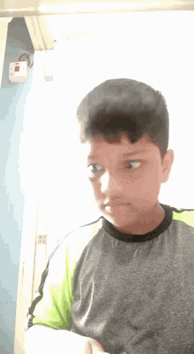a young boy wearing a gray shirt and green sleeves