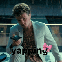 a man in a suit is holding a cell phone and the word yapping is on the bottom