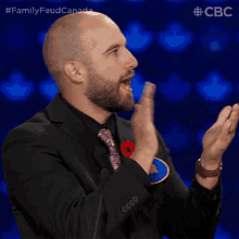 a man in a suit and tie with a poppy on his shirt is clapping his hands