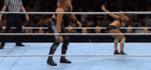 two women are wrestling in a ring while a referee watches