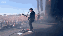 a man playing a guitar in front of a crowd with bbc written on the bottom right