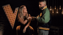 a man in a green jacket holds the hand of a woman