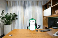 a cartoon penguin is sitting at a desk in front of a computer .