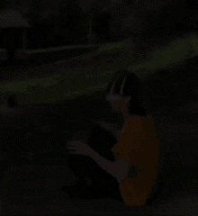 a man is sitting on the side of a road wearing a yellow shirt and a black hat .