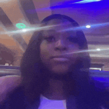 a woman is sitting at a table in a restaurant with a blurry background and a blue light shining on her face .