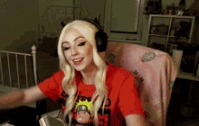 a blonde woman wearing headphones and a red shirt that says naruto on it