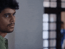 a close up of a man 's face with a blurry window in the background