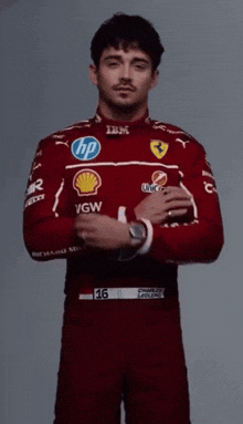 a man in a red ferrari uniform is adjusting his watch .