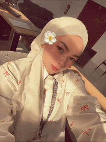 a woman wearing a white hijab takes a selfie with a flower in her hair