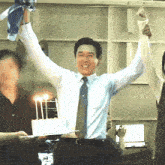 a man in a blue shirt and tie holds up his arms in the air