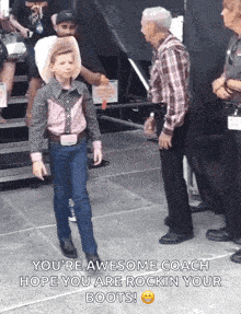 a young boy in a cowboy outfit is talking to a man in a plaid shirt