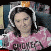 a woman wearing headphones and a pink shirt that says choked
