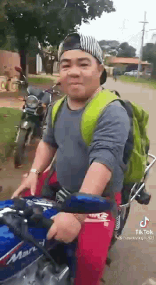 a man is riding a motorcycle down a street with a backpack on his back .