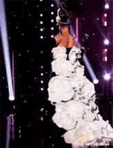 a woman in a long white dress is standing on a stage