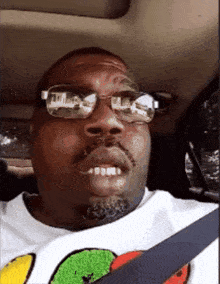 a man in a car wearing sunglasses and a shirt with a smiley face on it