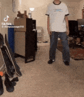 a man is standing in a living room with skateboards .