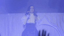 a woman singing into a microphone with a crowd behind her