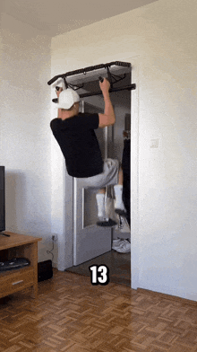 a man hangs upside down on a bar with the number 13 on the bottom right