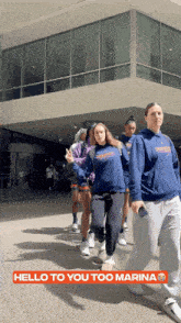 a group of people are walking in front of a building with the words hello to you too marina