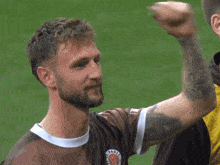 a man with a tattoo on his arm is wearing a shirt that says ' fc st pauli ' on it