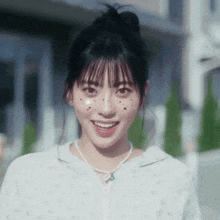 a girl with a bun on her head and a pearl necklace smiles at the camera