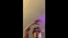 a man is dancing in a room with a purple light coming out of his hand .