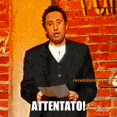 a man in a suit is holding a piece of paper that says attentato on it