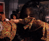 a woman wearing a colorful shirt covering her face
