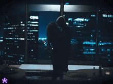 a man and woman are kissing in front of a window with cnr on it