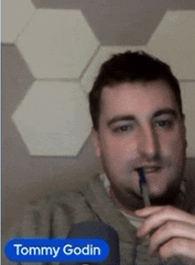 a man with a pen in his mouth and the name tommy godin below him