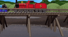 a blue train and a red train are crossing a bridge .