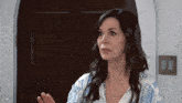 a woman wearing a blue and white shirt is talking to someone