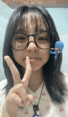 a girl wearing glasses is making a peace sign with her fingers