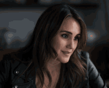 a woman wearing a black leather jacket looks down