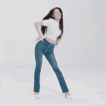 a woman in a white shirt and blue jeans is dancing in a white room .