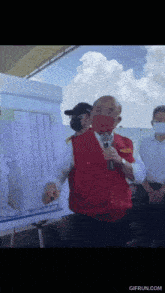 a man in a red vest is holding a microphone
