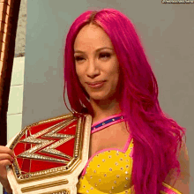 a woman with pink hair is holding a world heavyweight wrestling championship belt