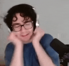 a young man wearing headphones and glasses is making a funny face .