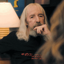 a man with long blonde hair and a beard is wearing a black shirt that says " for " on it