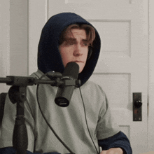 a man in a hooded sweatshirt is talking into a microphone