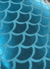 a close up of a blue fabric with a mermaid tail pattern