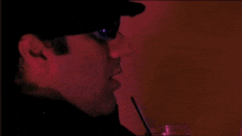 a blurry picture of a man wearing sunglasses and a straw