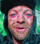 a man with a beard and blue eyes is wearing a black hooded jacket