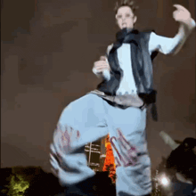 a man in a vest and jeans is dancing in front of a building