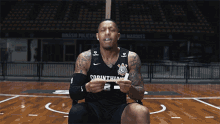 a man wearing a corinthian jersey sits on a court