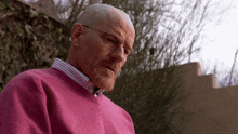 bald man wearing glasses and a pink sweater
