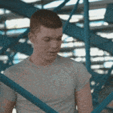 a man in a grey shirt stands in front of a blue railing