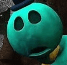 a close up of a green stuffed animal wearing a hat and a collar .